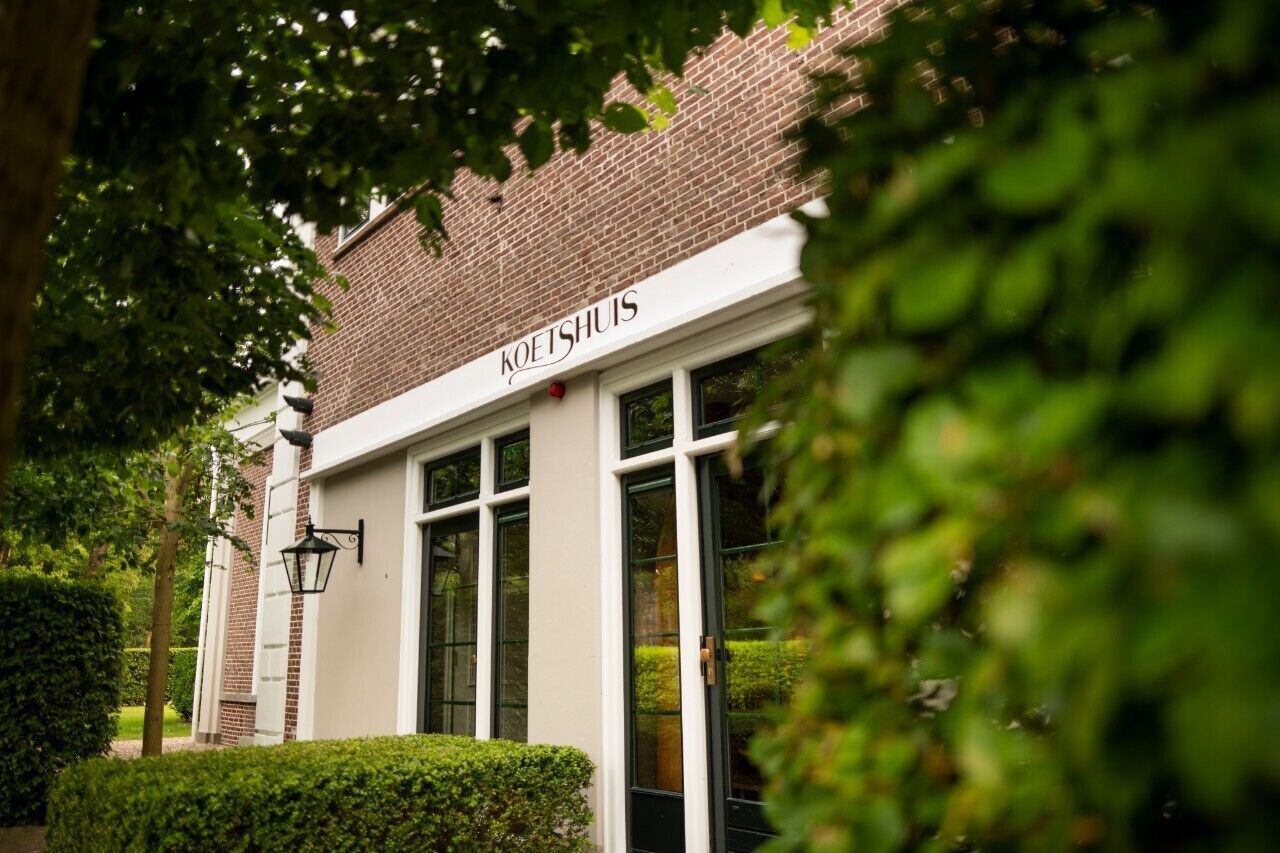 Een gebouw met een bord waarop 'KOETSHUIS' staat.