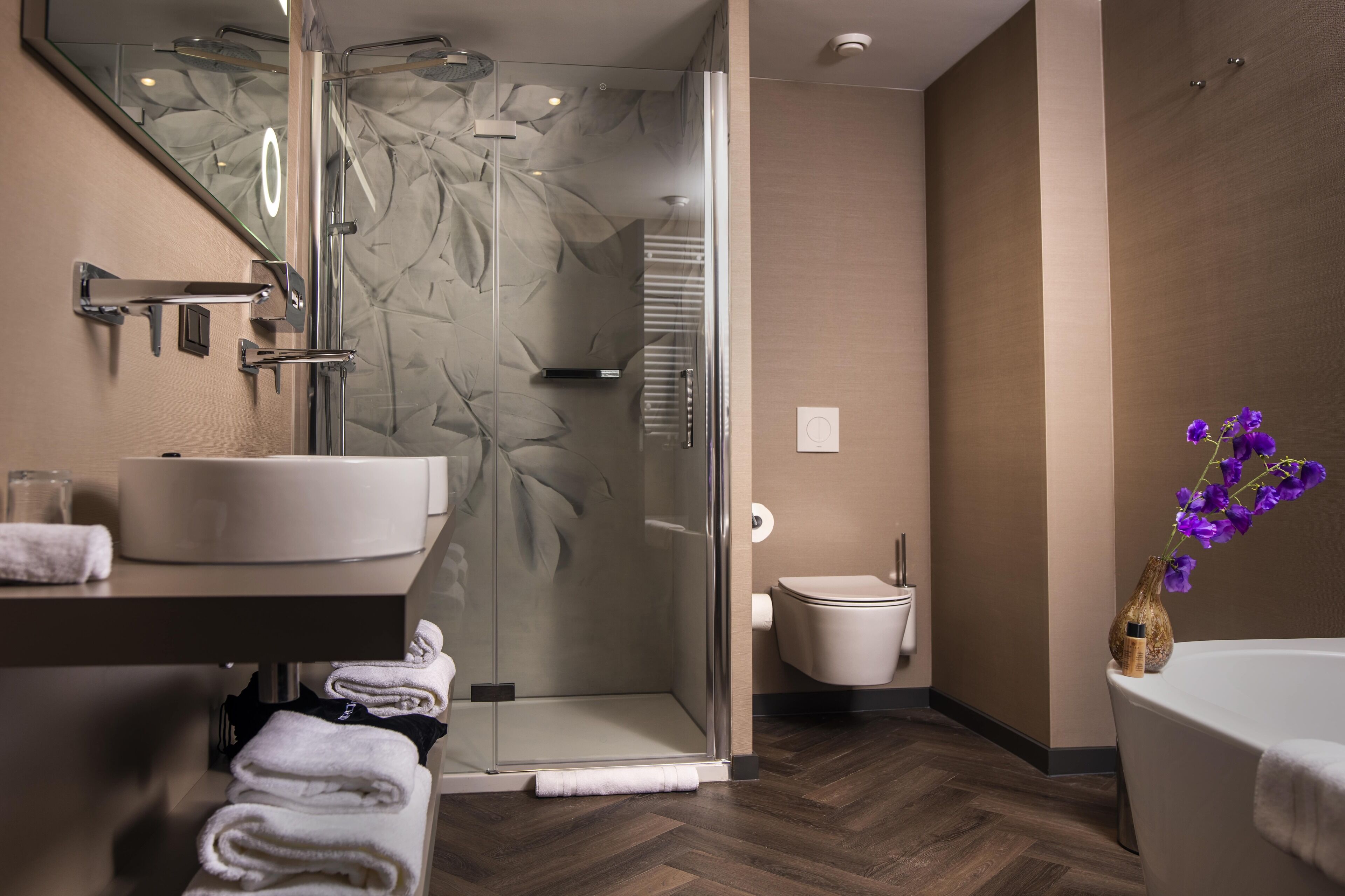 A modern bathroom with a glass-enclosed shower, a white sink, and a bathtub.