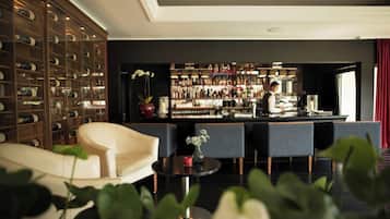A bar area with a bartender, a wine rack, and seating.