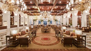 Un hall d’entrée spacieux, doté de plusieurs coins salon, d’un magnifique lustre et d’un grand tapis décoratif.