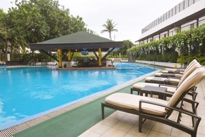 Una piscina al aire libre, sillones reclinables de piscina