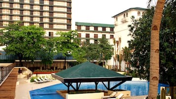 A rooftop pool area with lounge chairs, a gazebo, and a view of surrounding buildings.