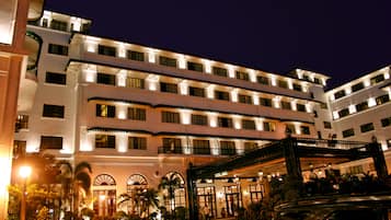 A multi-story hotel with a grand entrance, multiple balconies, and a well-lit facade.