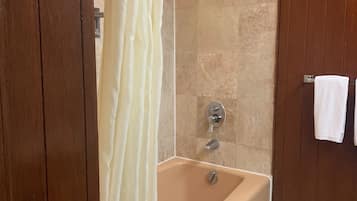 A bathroom with a bathtub, shower, and towel rack.