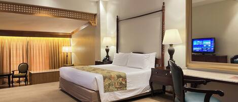A hotel room with a large bed, a desk with a chair, a television, and a mirror.