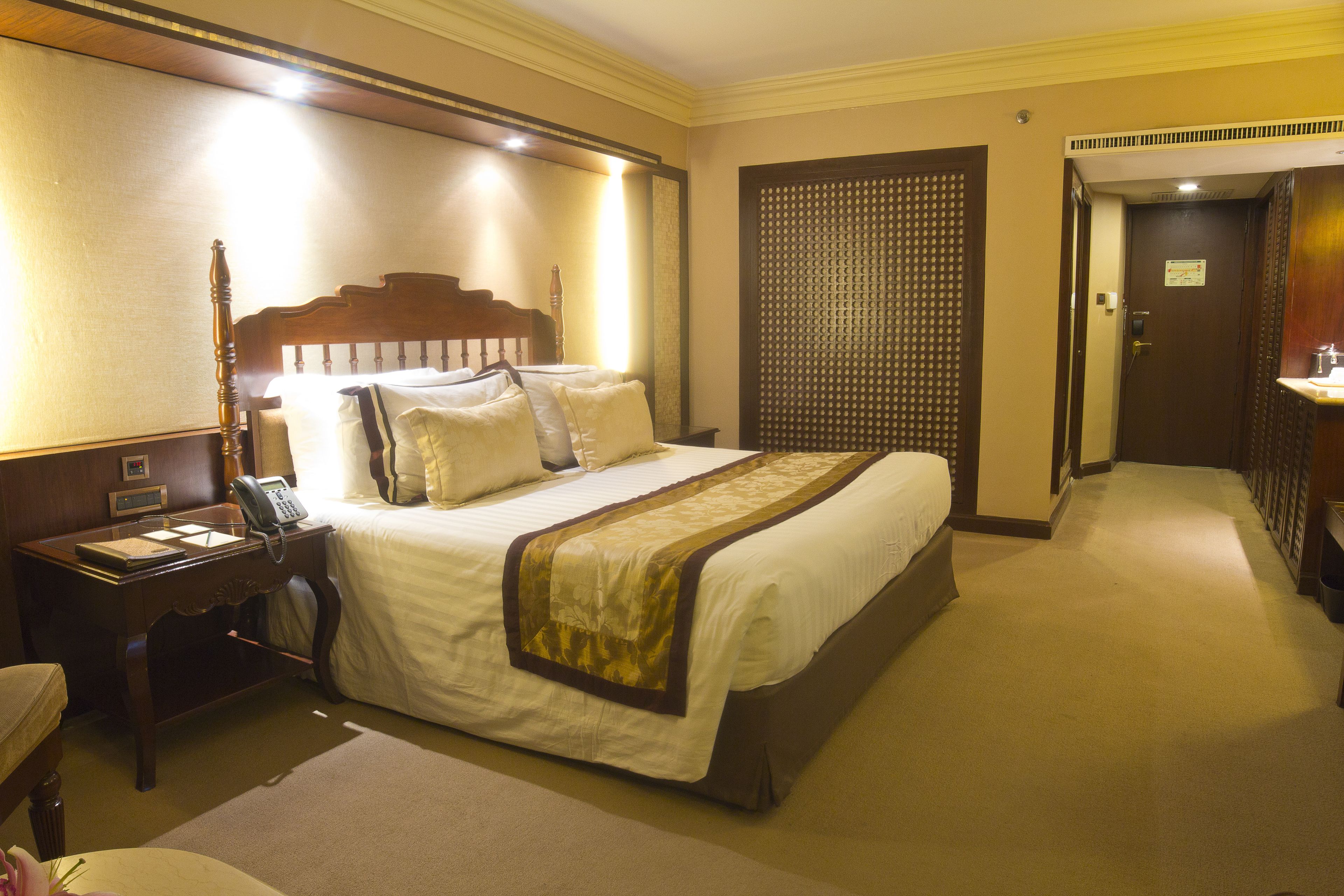 Una habitación de hotel con una cama grande, una mesita de noche con un teléfono y un escritorio con una lámpara.