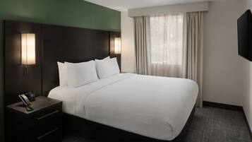 A hotel room with a large bed, a nightstand with a phone, and a window with curtains.