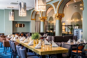 Un restaurante con una larga mesa dispuesta para comer, asientos acolchados y luminarias decorativas.