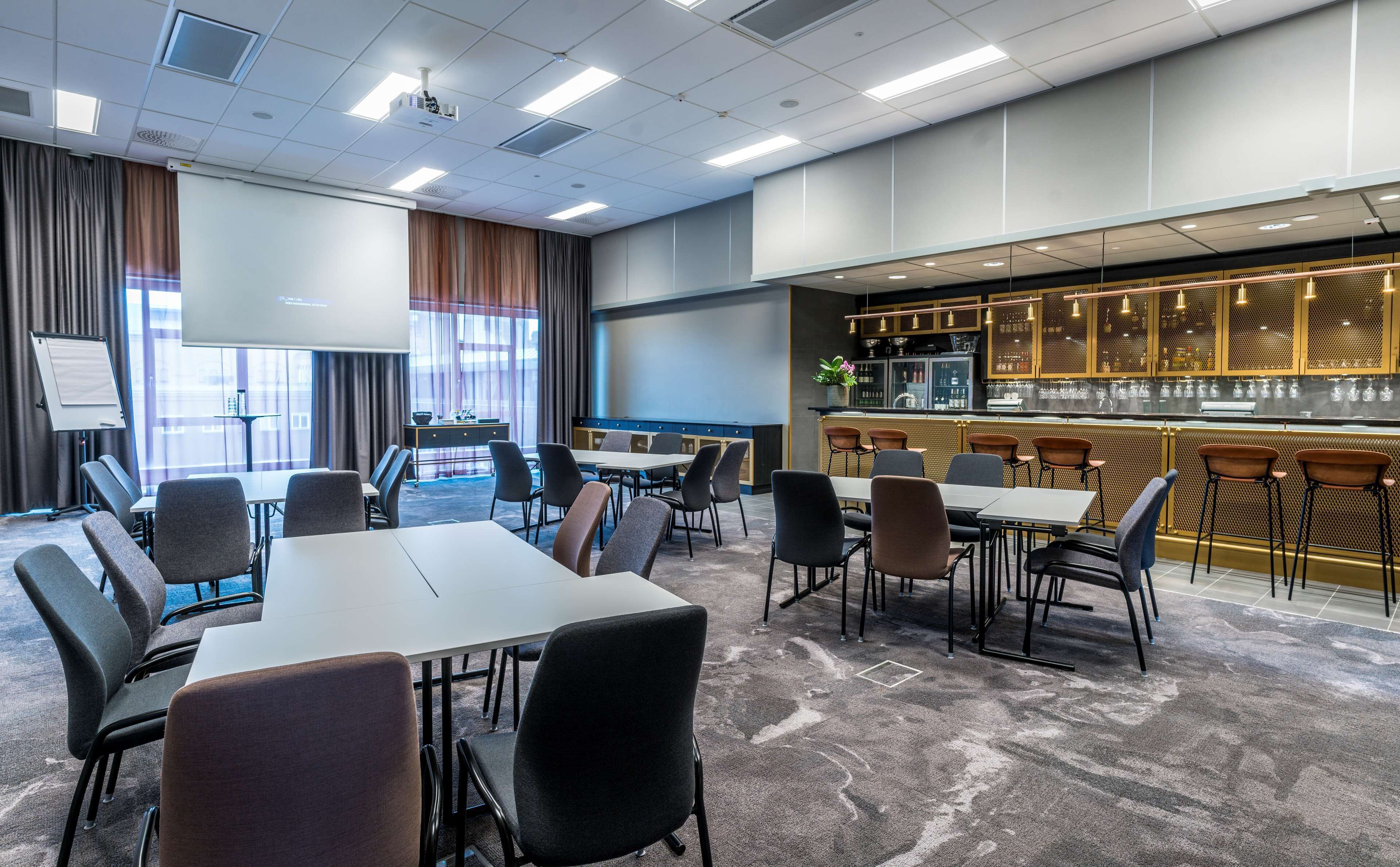 A conference room with a whiteboard, projector, and a bar area with stools and a counter.