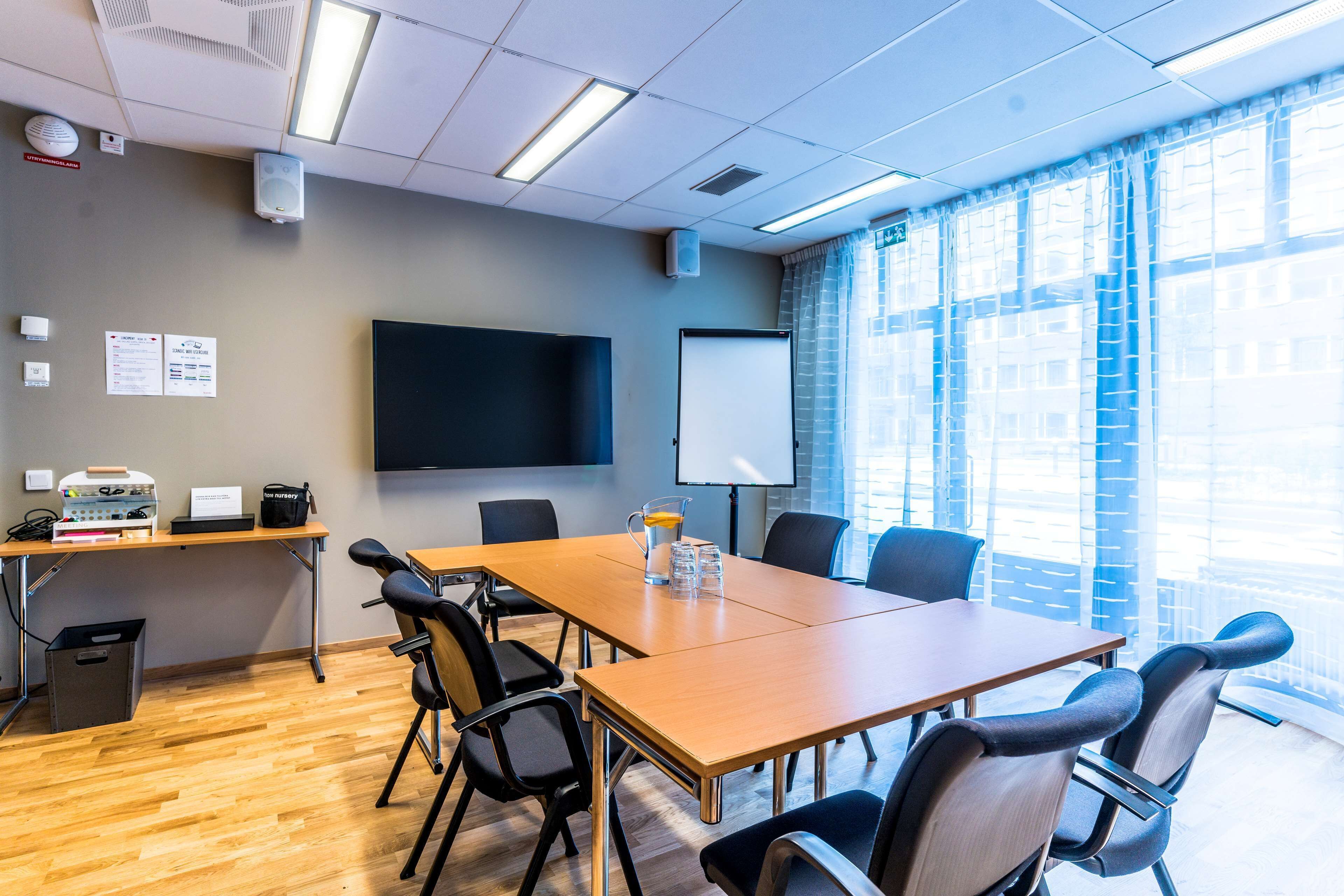 A conference room with a long table, chairs, a projector screen, and a whiteboard.