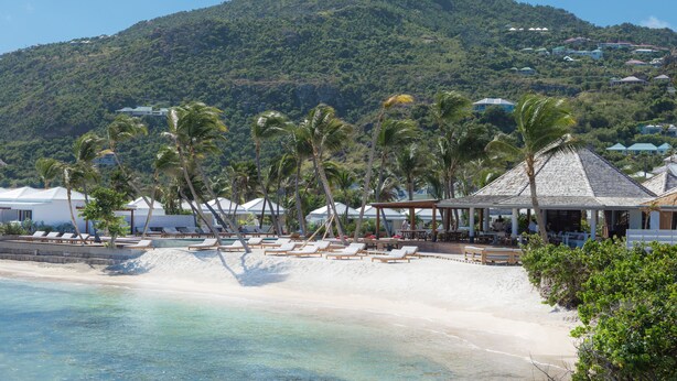 A beach resort with lounge chairs, a gazebo, and a mountain in the background. - Le Sereno (St. Barthelemy)