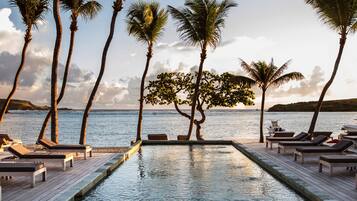 Una piscina al aire libre, sillones reclinables de piscina