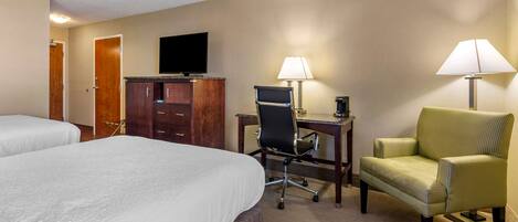 A hotel room with two beds, a desk with a chair, a television, and two lamps.