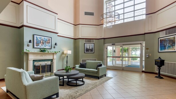 A spacious lobby with a fireplace, two sofas, a round table, and a chandelier.