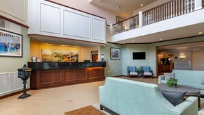 A spacious lobby with a reception desk, seating area, and a balcony.