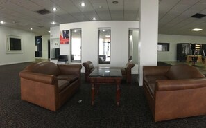 A conference room with leather sofas, a marble table, and a large mirror. - FairBridge Inn Express Melrose Park (Melrose Park)