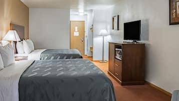 Una camera d'albergo con due letti, una televisione, una scrivania e un armadio.