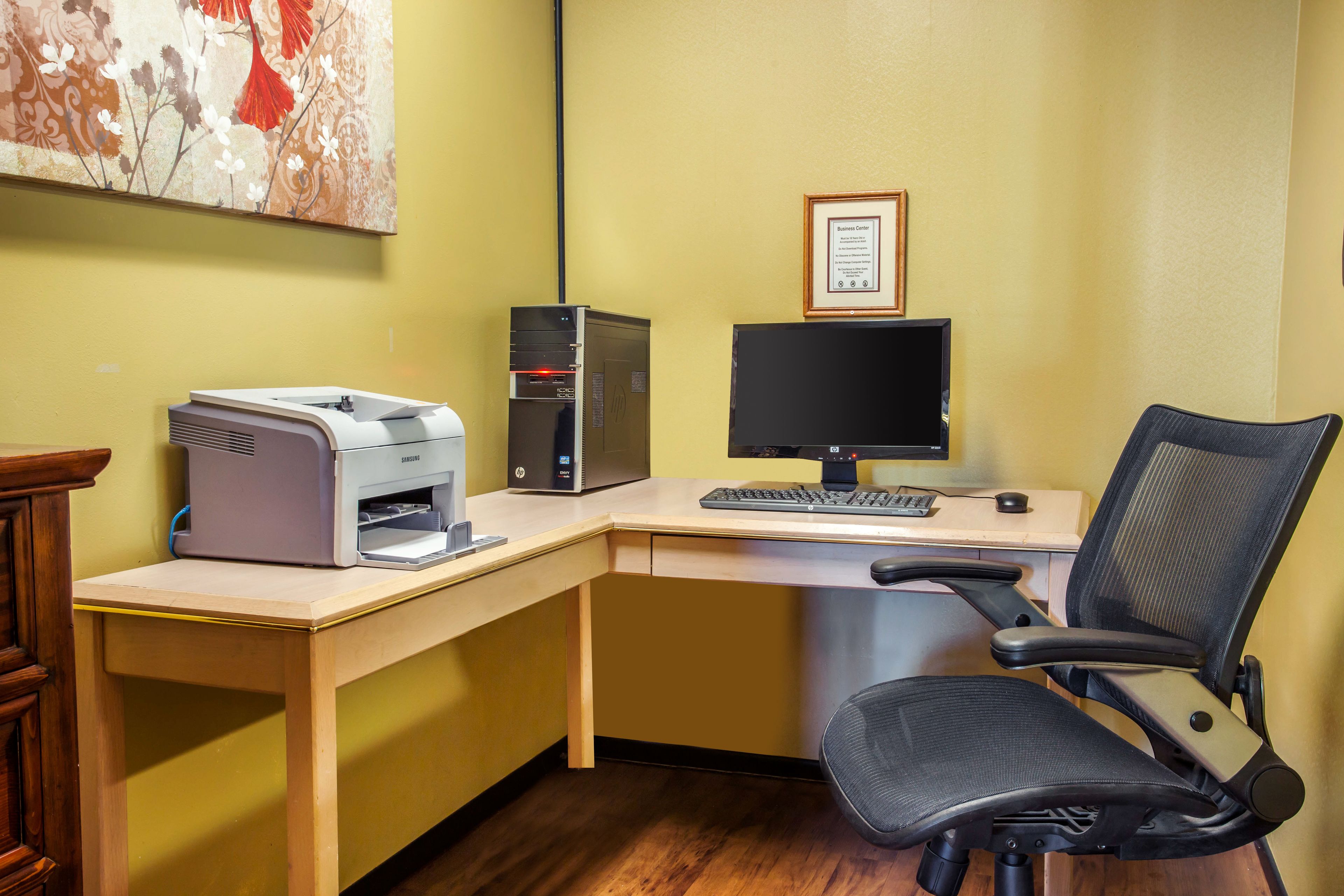 Een hoek kantoor met een bureau, een printer, een computer en een stoel.