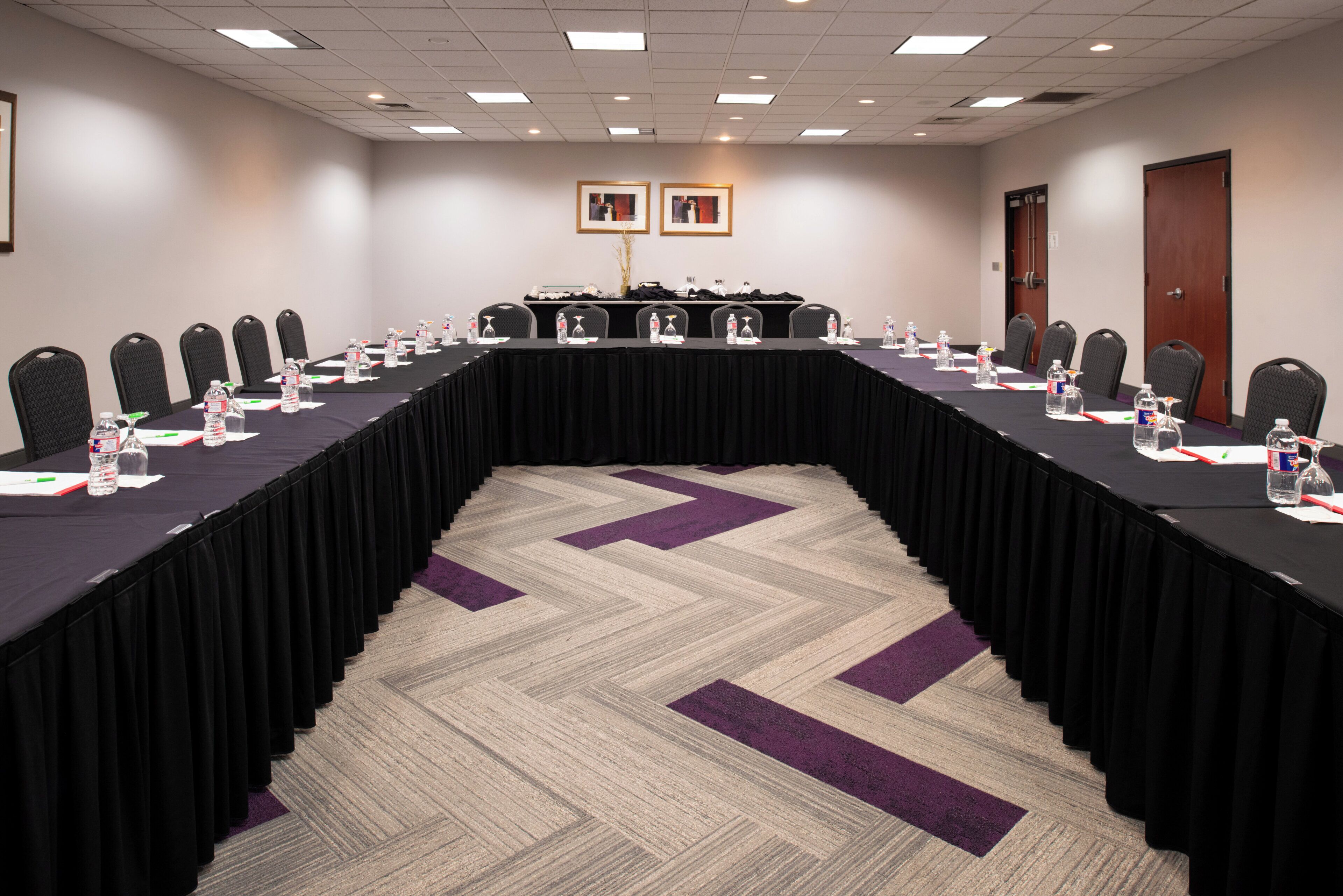 A conference room with a long table, chairs, water bottles, and name cards.
