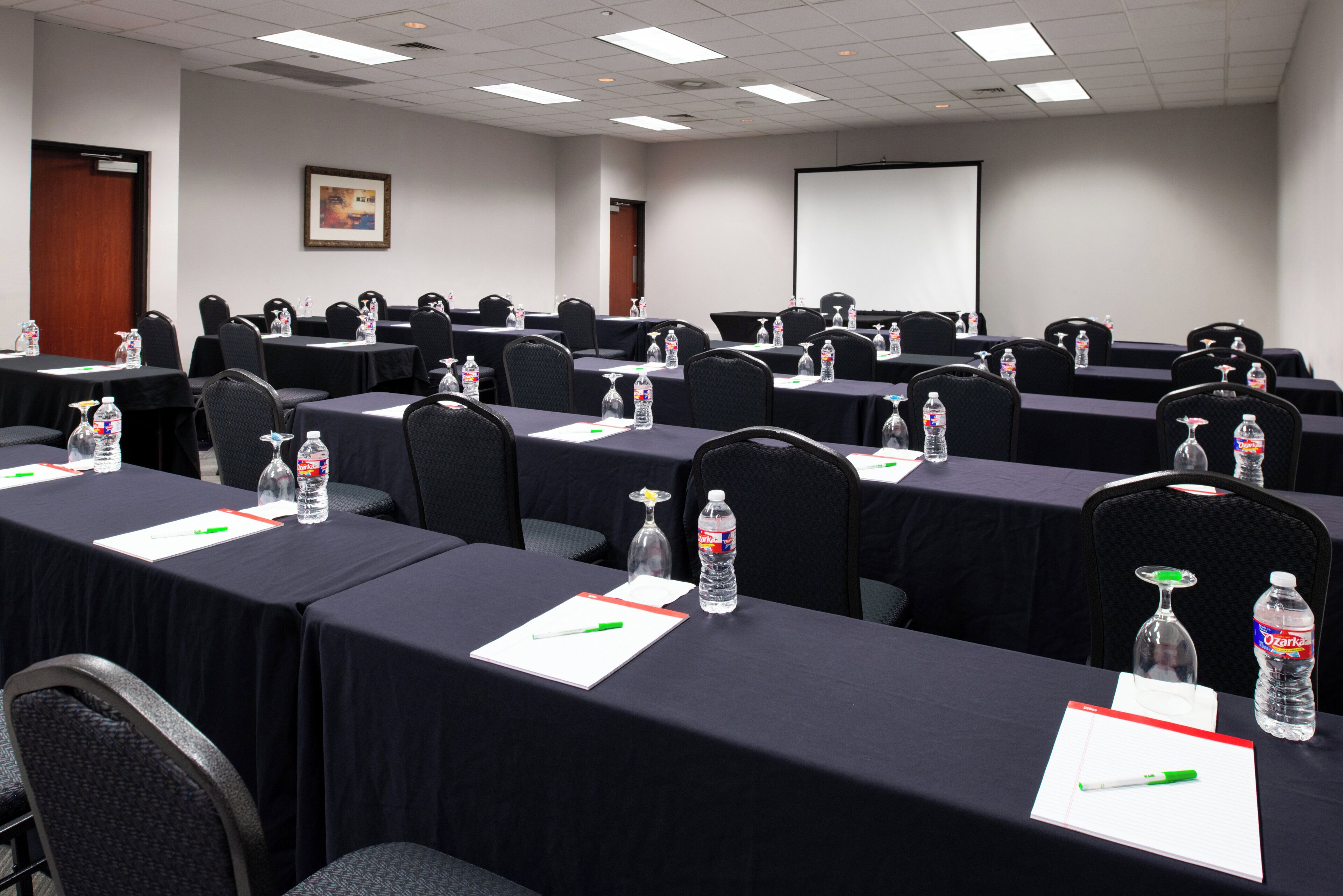 A conference room with rows of tables, chairs, water bottles, and nameplates.