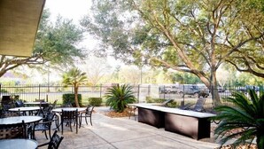 Un patio al aire libre con mesas, sillas, una barra y un cerramiento.