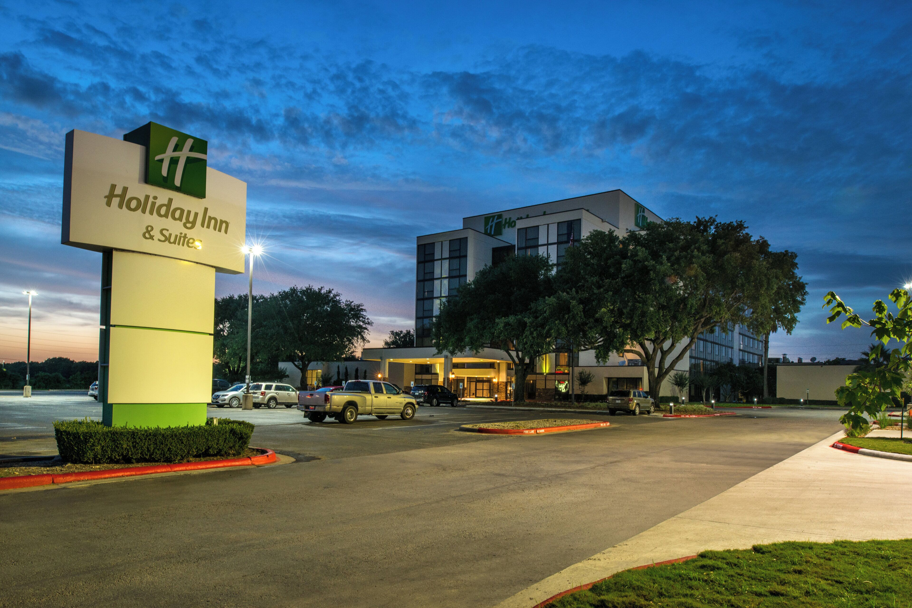A Holiday Inn & Suites with a modern building and a parking lot.