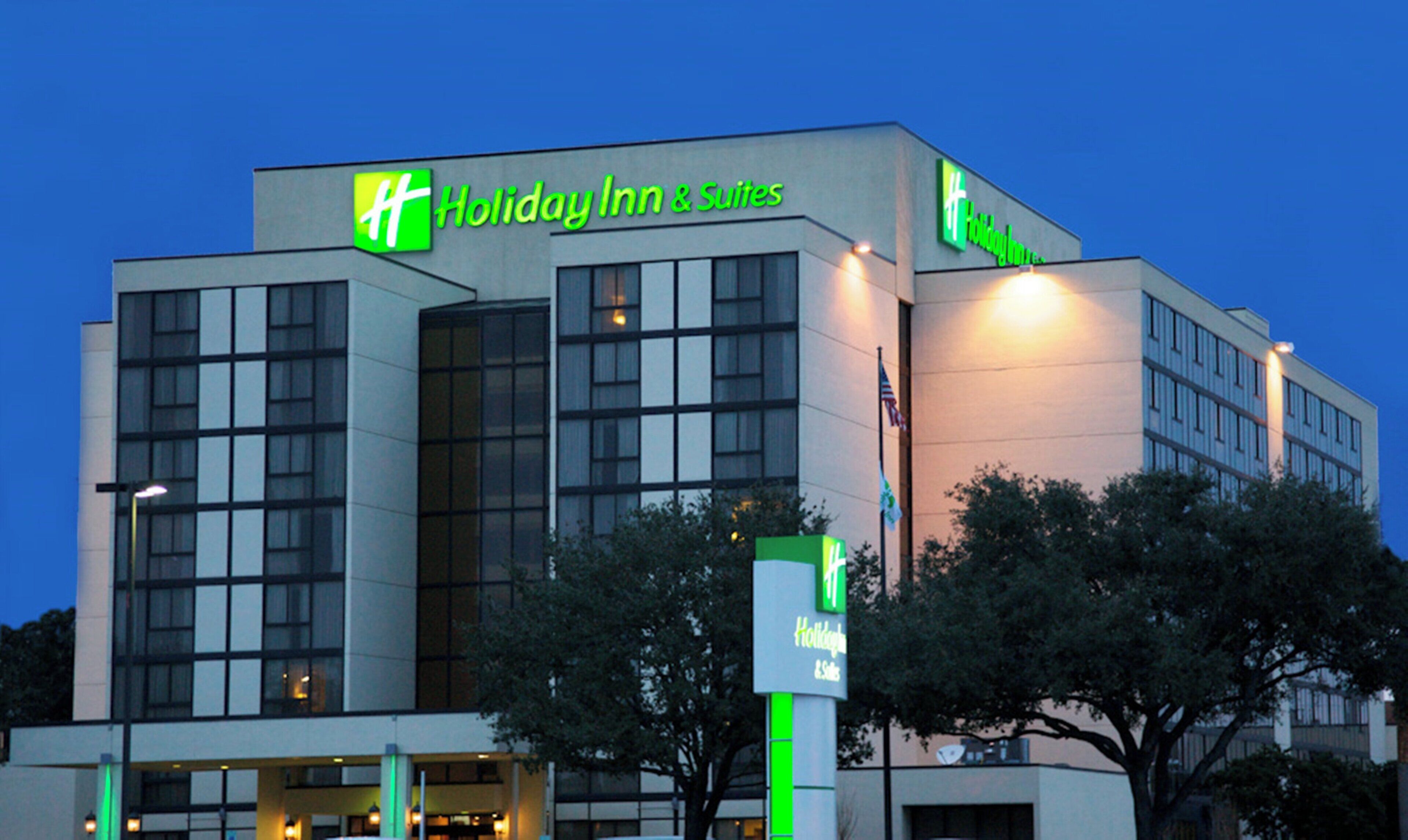 Un edificio de Holiday Inn & Suites con diseño moderno, ventanas amplias y un logotipo verde destacado.