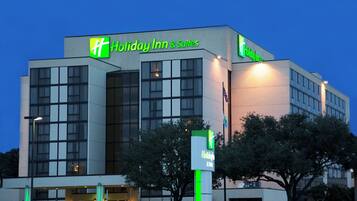Un edificio de Holiday Inn & Suites con diseño moderno, ventanas amplias y un logotipo verde destacado.