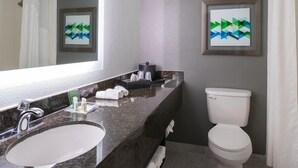 Un baño con lavamanos de mármol, inodoro y dos obras de arte enmarcadas en la pared.