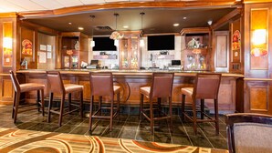 A bar area with a curved counter, multiple stools, and a patterned carpet. - Wyndham Omaha / West Dodge (Omaha)