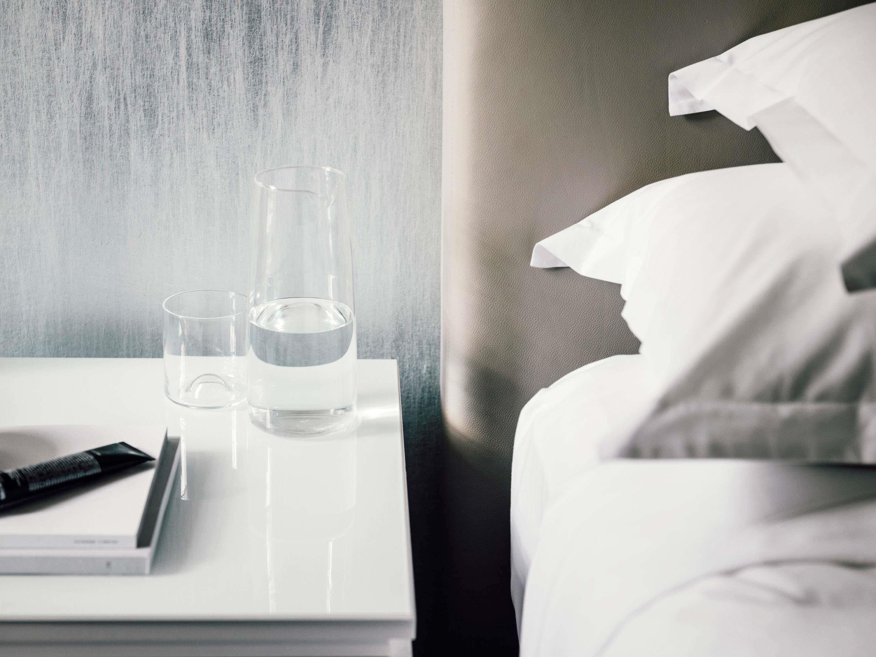 A hotel room with a bed, a bedside table, and a nightstand.