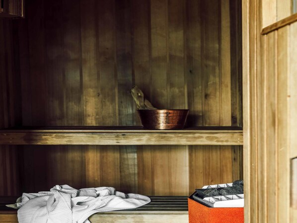 A rustic wooden interior with a metal bucket on a shelf, a towel on the floor, and a box with a patterned design.