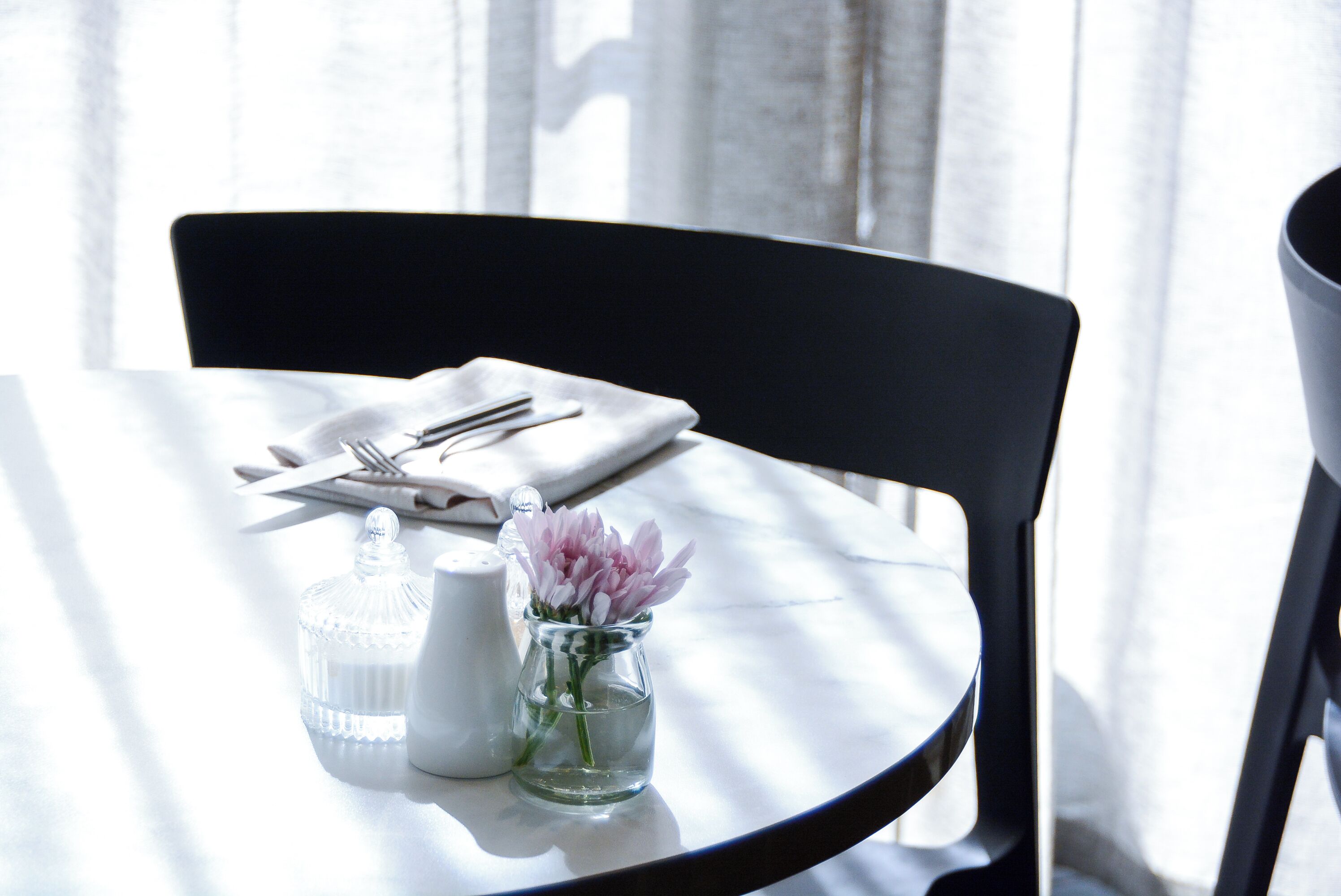 A table set with a clear glass pitcher, a salt and pepper shaker, and a small vase with flowers.