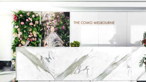 A reception area with a marble counter, a floral wall, and a sign reading "THE COMO MELBOURNE". - The Como Melbourne by Accor (South Yarra)