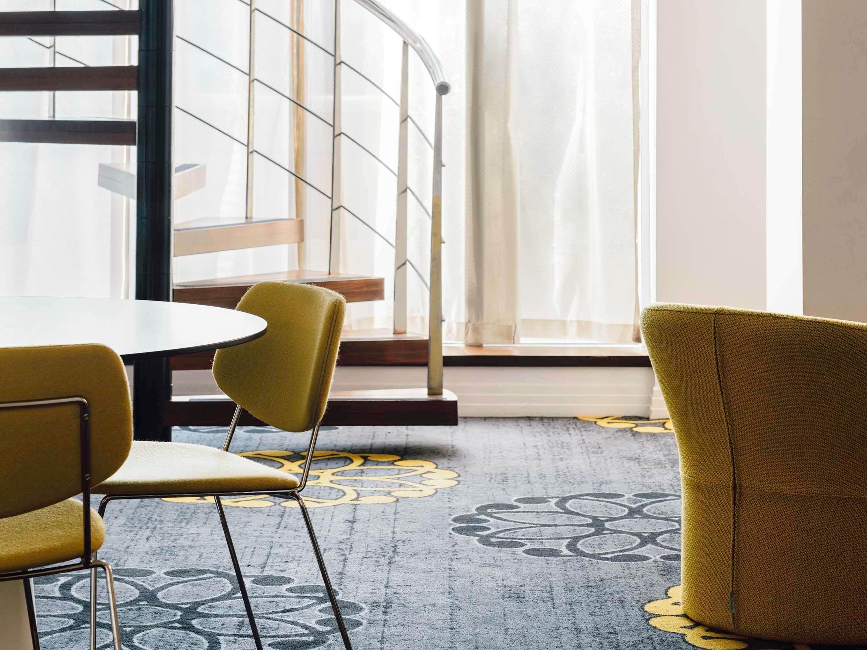 Un intérieur moderne avec une table ronde, deux chaises jaunes et un tapis à motifs.