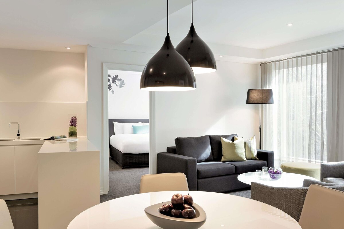 A modern hotel room with a dining area, a sofa, and a bed.