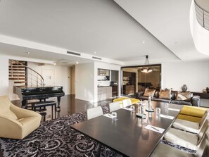 A modern living room with a piano, a dining table, and a sofa.