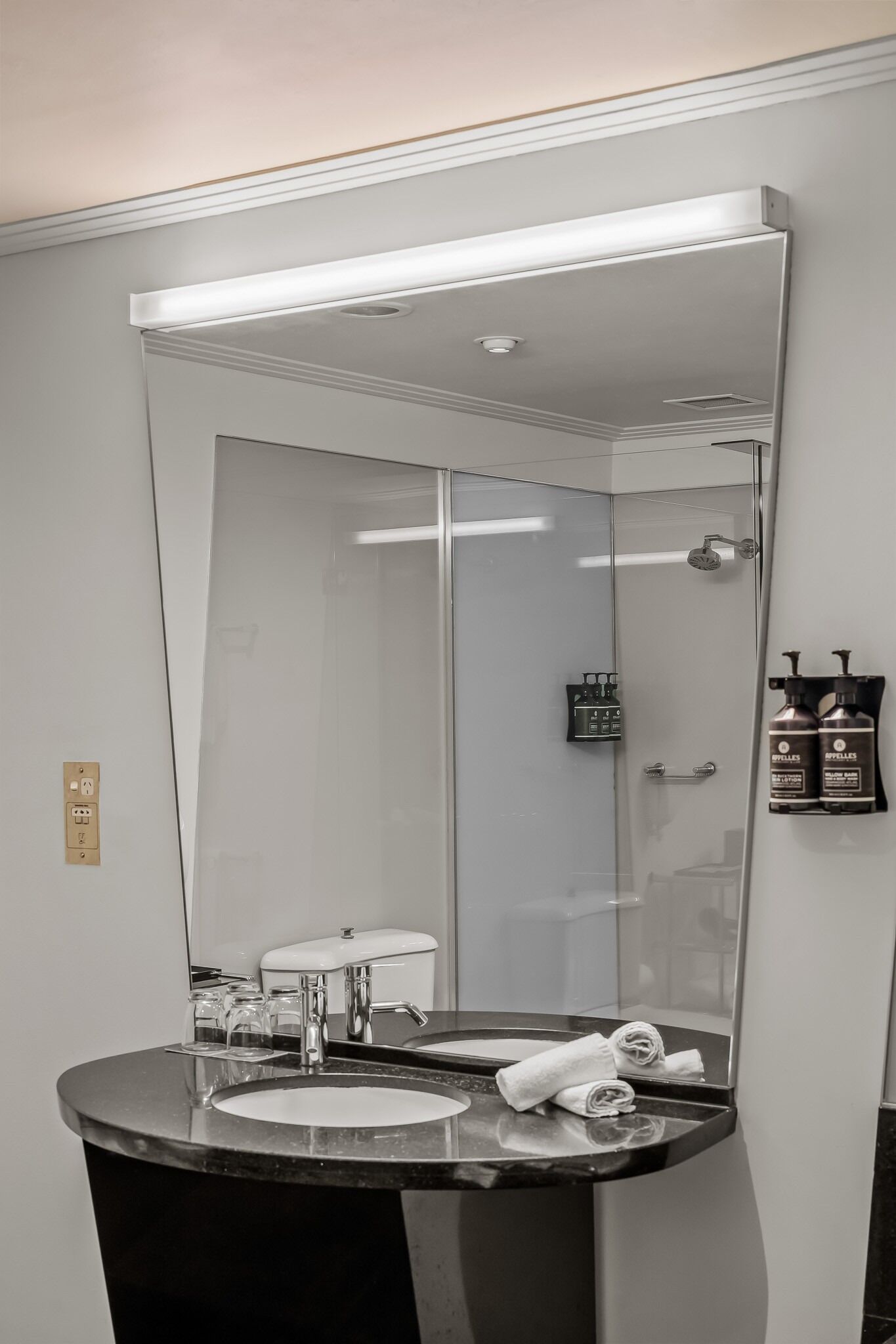Un baño con un espejo grande, un lavabo, una ducha y un perchero para toallas.