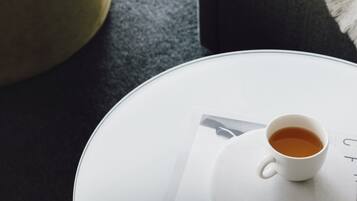 Una habitación acogedora con una mesa redonda, una taza de té y una silla con una manta.