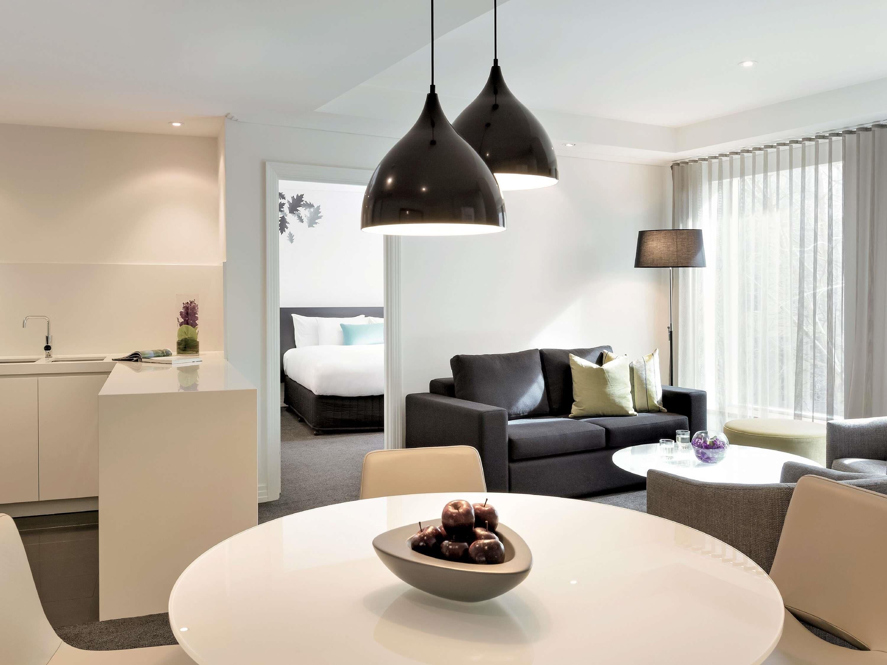 Una habitación de hotel moderna con zona de comedor, sofá y cama.