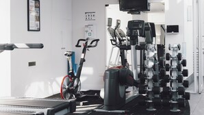 A modern gym with cardio machines, weight stations, and a stationary bike. - The Como Melbourne by Accor (South Yarra)