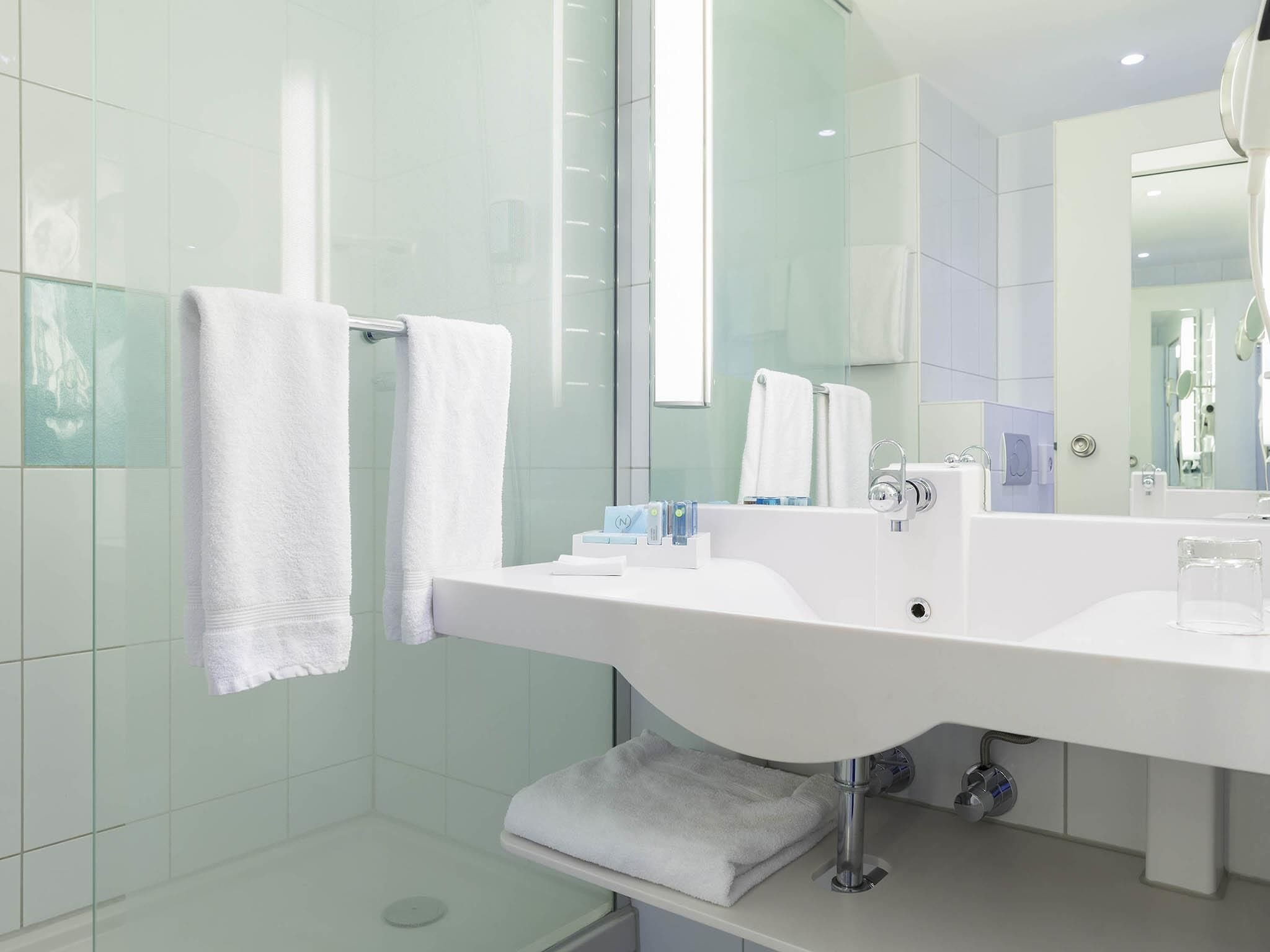Un baño moderno con un lavamanos grande de color blanco, un box de ducha de vidrio y un espejo sobre el lavamanos.