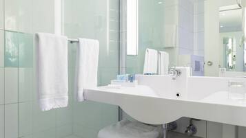 Un baño moderno con un lavamanos grande de color blanco, un box de ducha de vidrio y un espejo sobre el lavamanos.