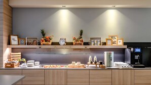 A modern kitchen with wooden cabinets, a coffee station, and a water dispenser. - Novotel Frankfurt City (Frankfurt)