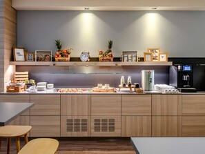 A modern kitchen with wooden cabinets, a coffee station, and a water dispenser. - Novotel Frankfurt City (Frankfurt)
