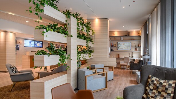 A modern hotel lobby with a reception desk, seating area, and a plant wall. - Novotel Frankfurt City (Frankfurt)