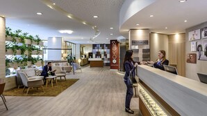 A modern hotel lobby with a reception desk, seating area, and a wall with a 'NOVO 2' sign. - Novotel Frankfurt City (Frankfurt)