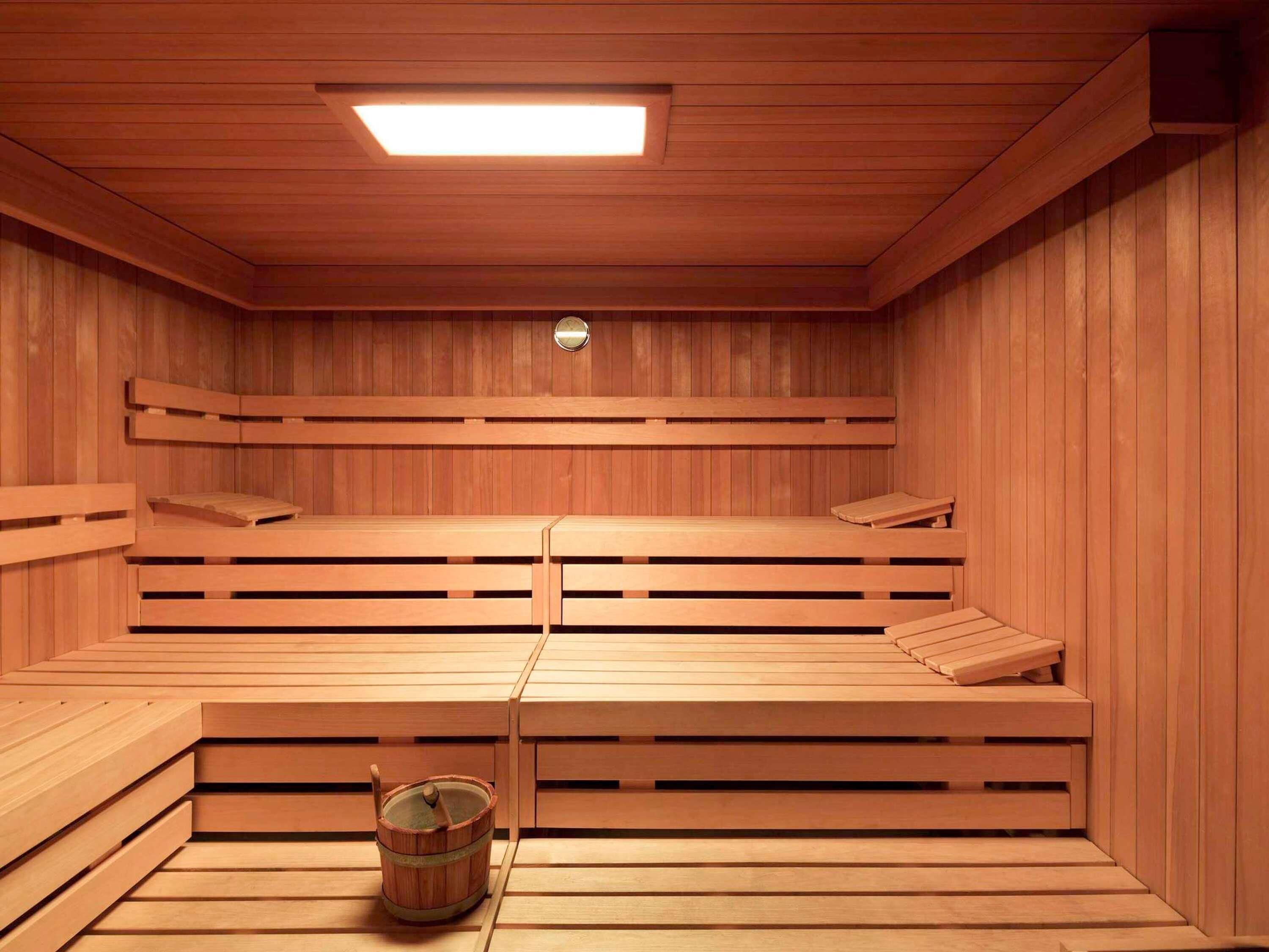 A sauna room with wooden benches and a bucket.