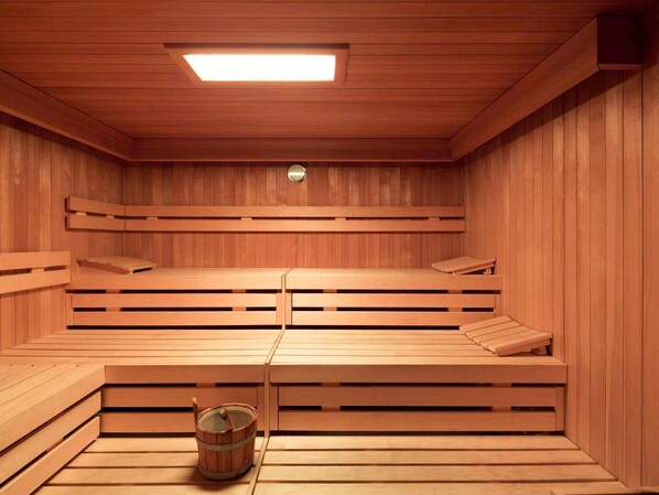 A sauna room with wooden benches and a bucket.