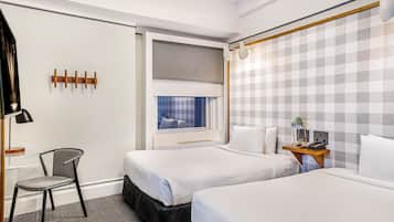 A hotel room with two beds, a desk, a chair, and a window with a view.
